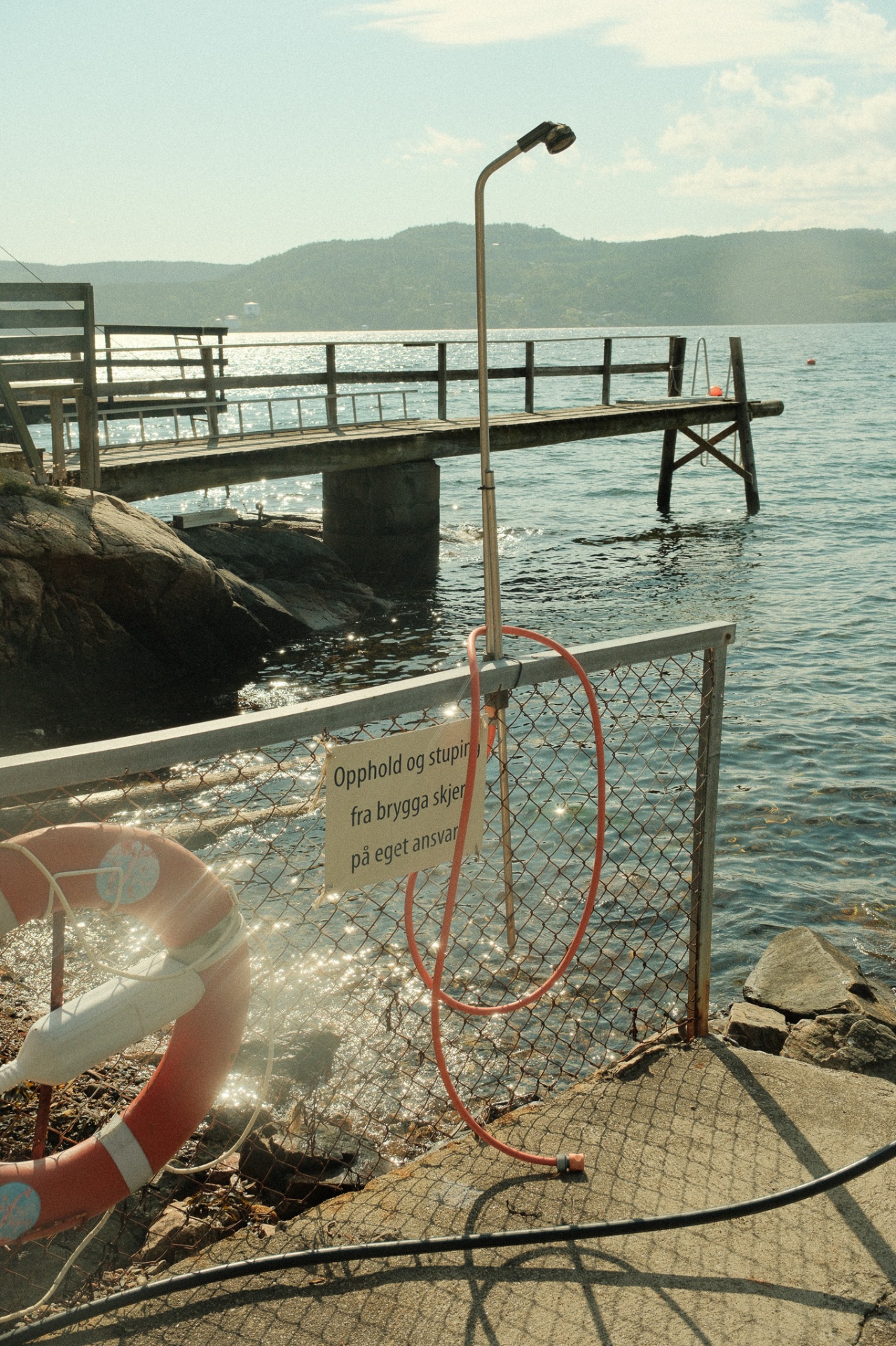 A wooden pier and outdoor shower at the Sjøboden swimming spot in Hvitsten.